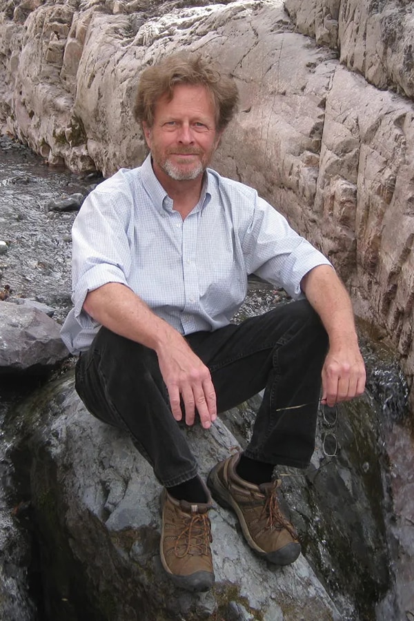 David Mason sitting on rock in stream bed