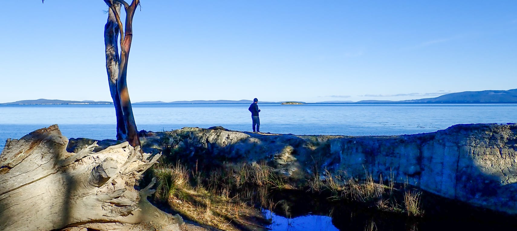 David looking out across blue water to distant shores