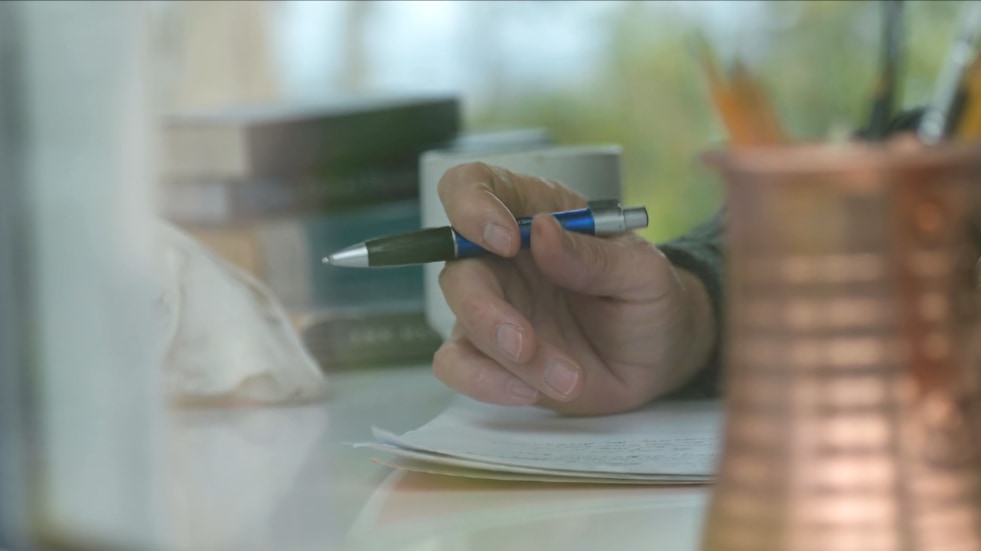 hand holding pen pauses in writing