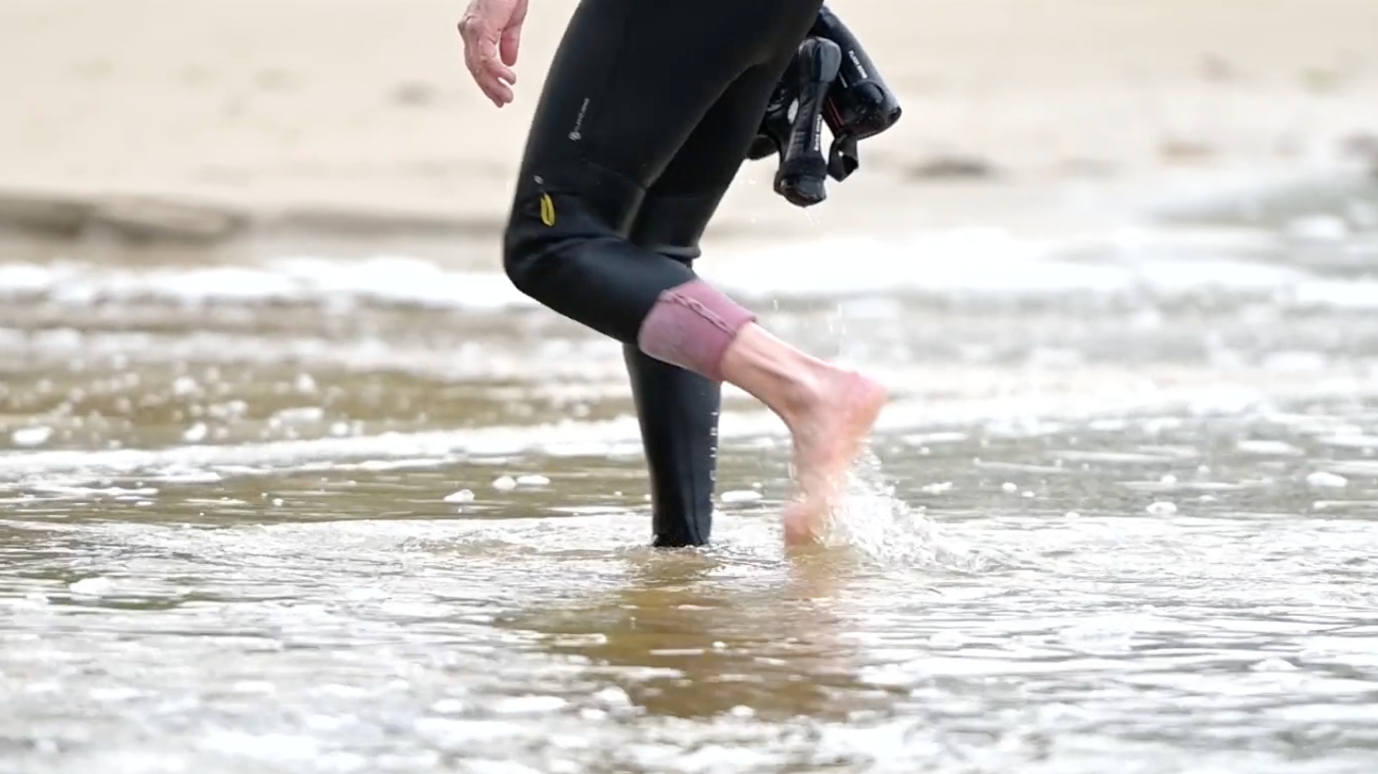 man in wetsuit walking through water